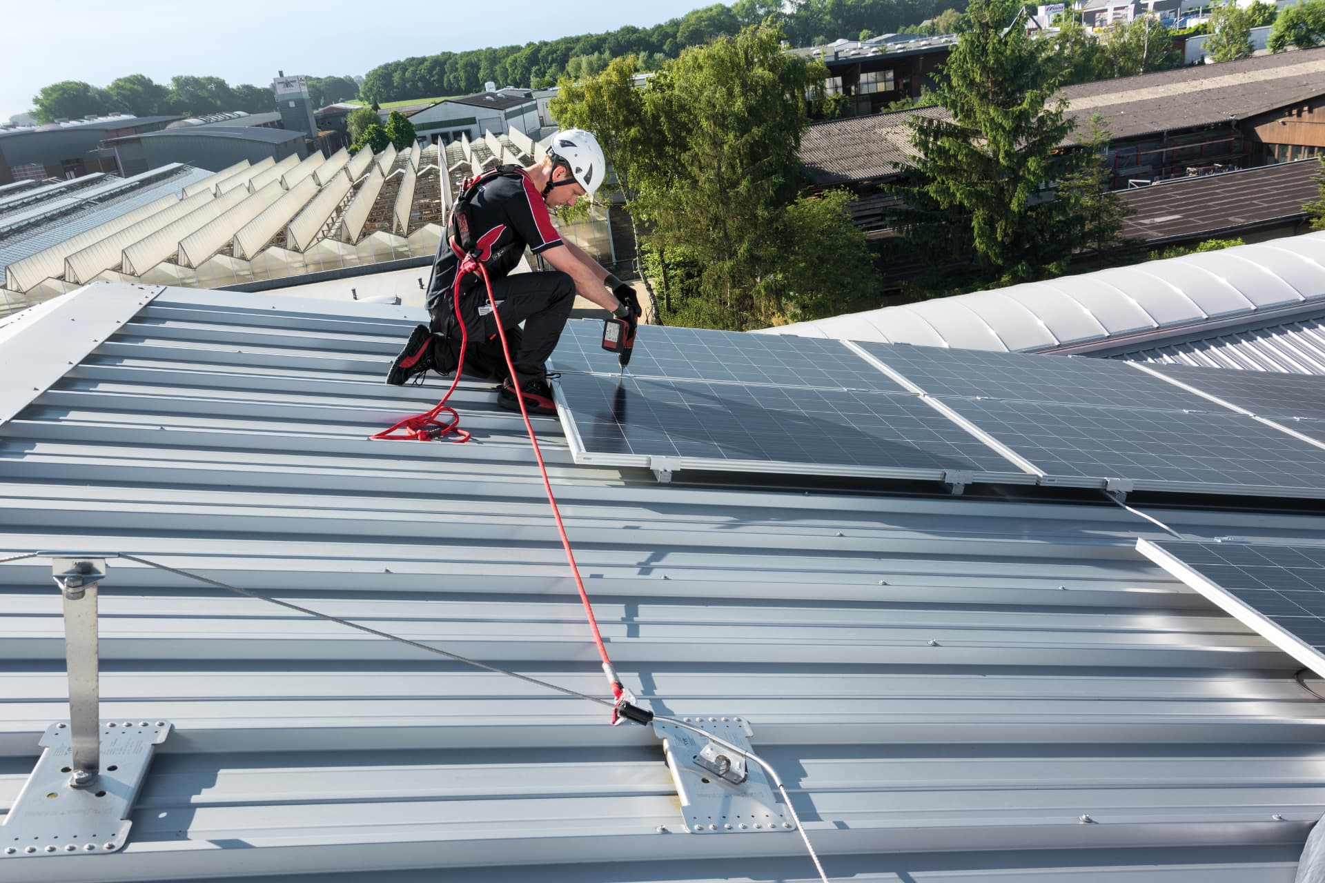Monteur aangelijnd aan een kabelsysteem tijdens werkzaamheden aan zonnepanelen